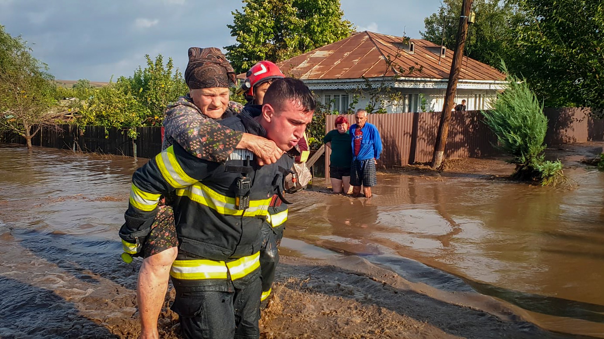 Hasič odnáša na chrbte staršiu ženu počas záplav v obci Cudalbi na východe Rumunka.