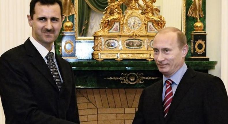 Russian President Vladimir Putin shakes hands with Syrian President Bashar Assad.