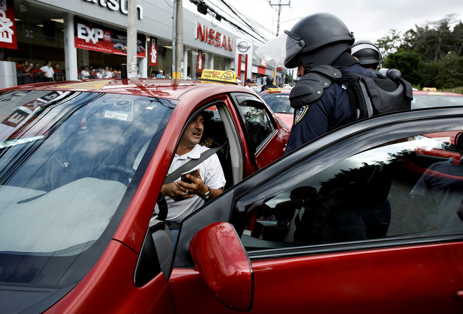 Riot police detain a taxi driver during a protest against ride-hailing service Uber in San Jose, Costa Rica, August 9, 2016.