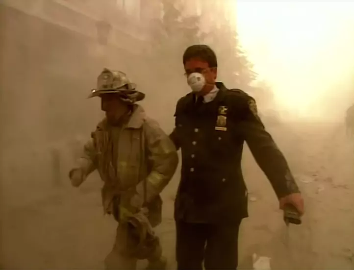 Oficer straży pożarnej eskortuje swego podwładnego ze strefy pyłu