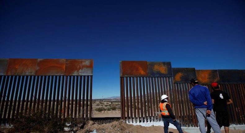 A worker and residents at a newly built section of the US-Mexico border fence at Sunland Park, Texas, opposite the Mexican border city of Ciudad Juarez, on January 26.