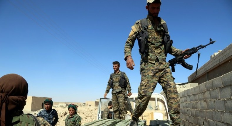 SDF fighters unload boxes of ammunition supplied by the US-led coalition in a village north of Raqa on June 7, 2017