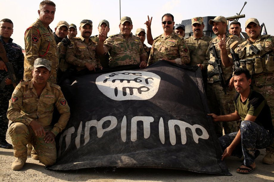 Iraqi soldiers celebrate as they pose with the Islamic State flag along a street of the town of al-Shura