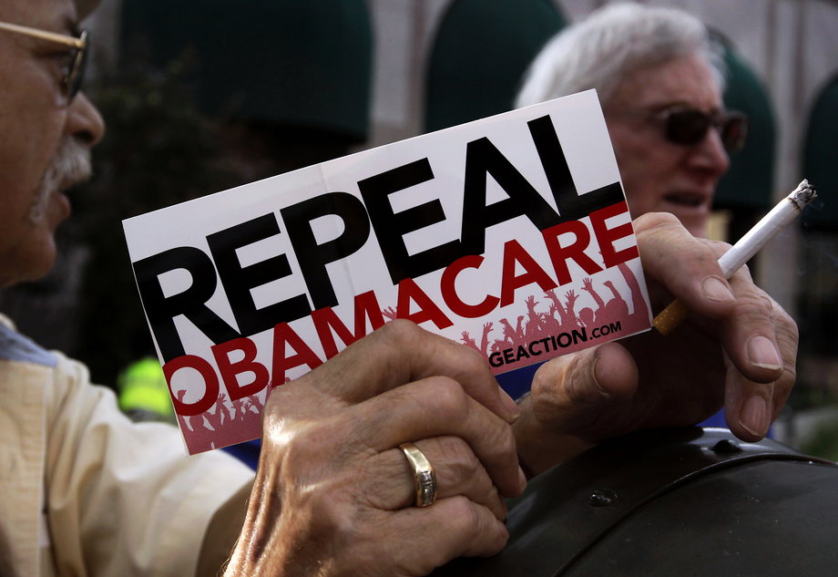 A small group of demonstrators stand outside of the HIlton Hotel and Suites prior to former South Carolina Senator Jim DeMint, president of the The Heritage Foundation, speaking at a "Defund Obamacare Tour" rally in Indianapolis August 26, 2013.