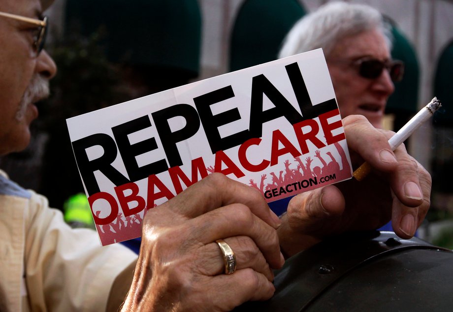 A small group of demonstrators stand outside of the HIlton Hotel and Suites prior to former South Carolina Senator Jim DeMint, president of the The Heritage Foundation, speaking at a "Defund Obamacare Tour" rally in Indianapolis August 26, 2013.