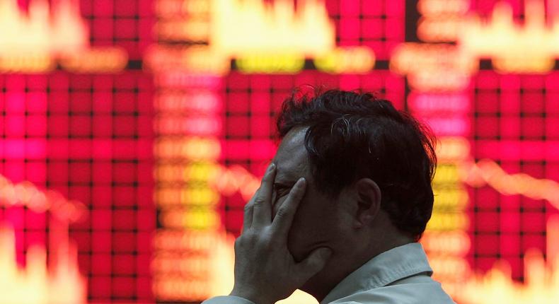 A man covers his face as he reads information displayed on an electronic screen at a brokerage house in Shanghai May 17, 2010.REUTERS