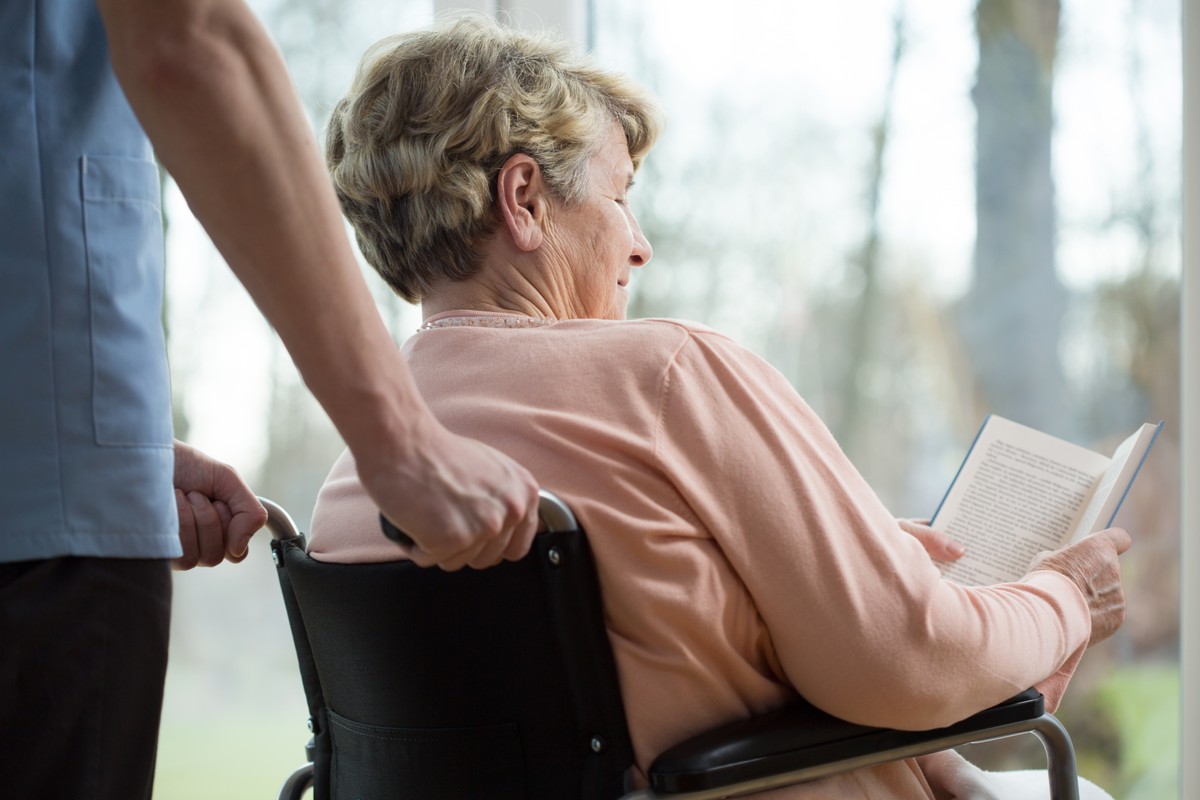 Disabled,Woman,Reading,Book,In,Retirement,Home