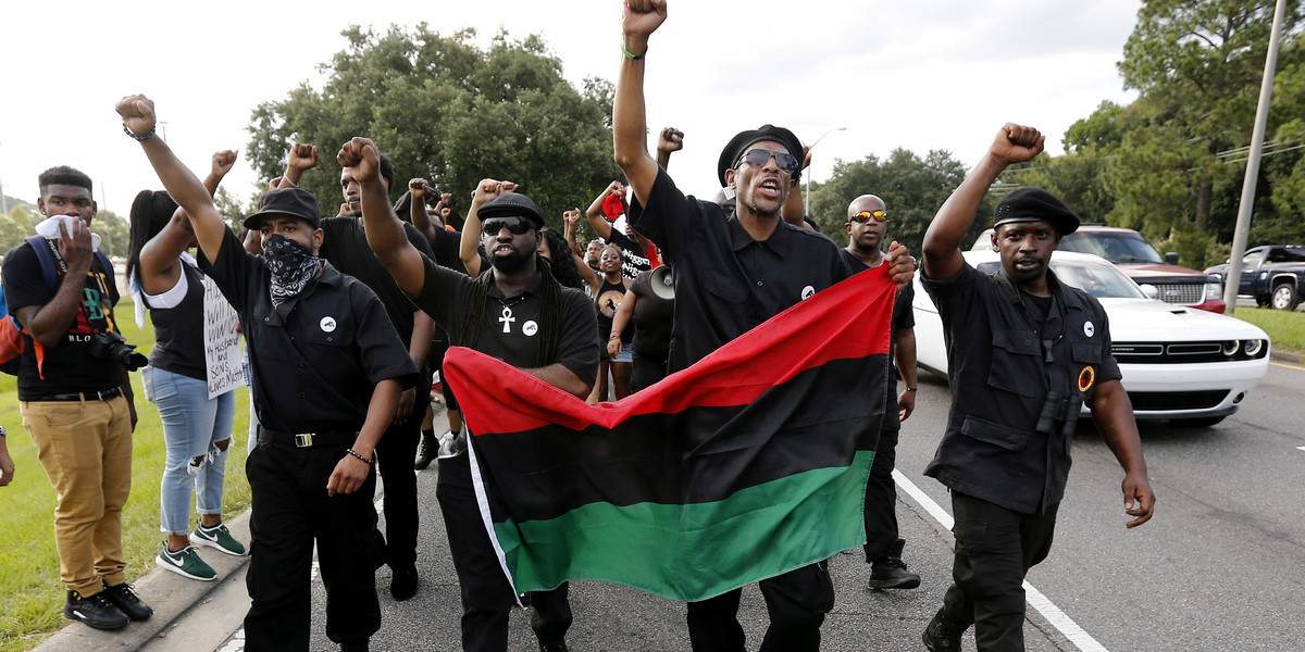 Demonstrators, wearing the insignia of the New Black Panthers Party, protest the shooting death of Alton Sterling near the headquarters of the Baton Rouge Police Department.