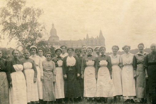 Niższa służba książańska (m.in. pokojówki i pomoce kuchenne) na tle widoku na Książ od strony północnej. Zdjęcie Louisa Hardouina wykonane w punkcie widokowym na życzenie Daisy, 1918 r. Kolekcja zamku Książ w Wałbrzychu