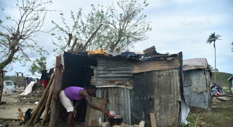 A woman prepares food on October 22, 2016 outside her home in the neighborhood of Gebeaux in the commune of Jeremie, southwestern Haiti, which was hit hard by Hurricane Matthew