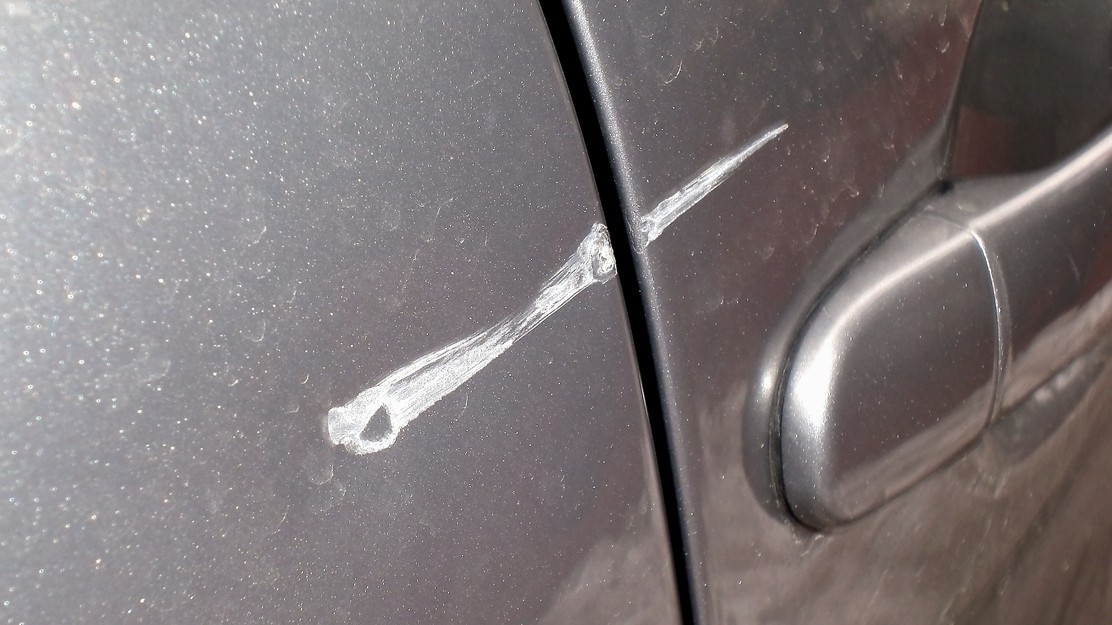 Charakteristický oblúkovitý škrabanec na bočnici auta prezradí otvorené dvere susedného vozidla na parkovisku ako najpravdepodobnejšieho páchateľa. 