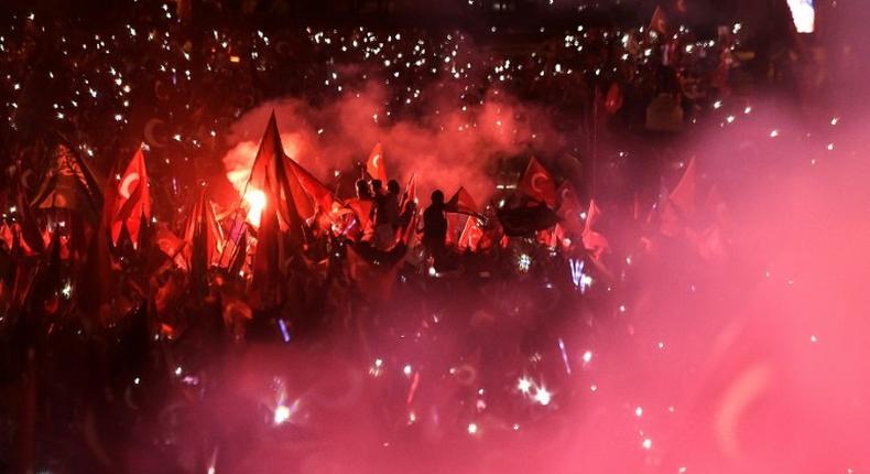 People wave Turkish national flags as Turkish President adresses a speech on July 15, 2017 during the first anniversary of failed coup in Istanbul