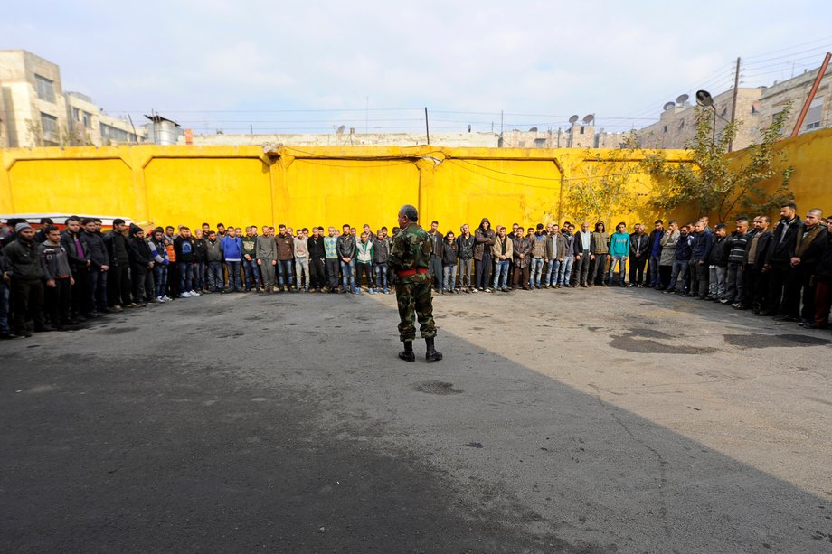 A police brigadier general addressing men who were evacuated from the eastern districts of Aleppo as part of a preparation Sunday to begin their military service.