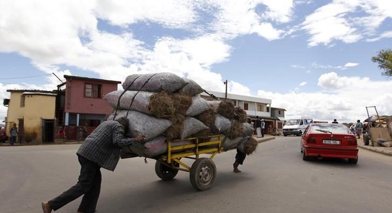 Men push charcoal for sale on a handcart along the streets of Madagascar's capital Antananarivo, December 22, 2013.    REUTERS/Thomas Mukoya