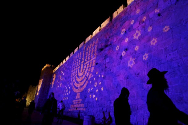 People walk past an image of a Menorah, the Hebrew name for the candle-holder used during the Jewish