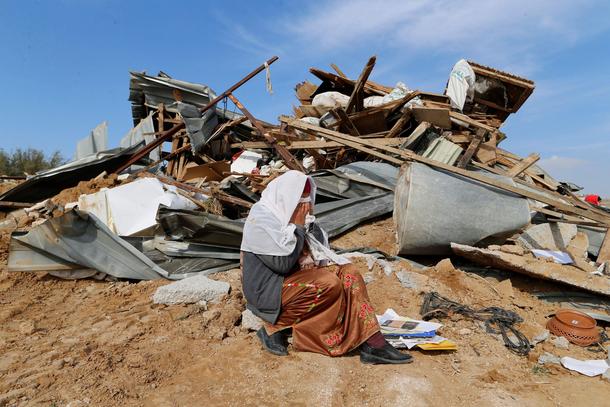 An Arab Israeli woman sits next to ruins from her dwellings which were demolished by Israeli bulldoz