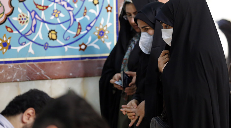 Iráni emberek szájmaszkban állnak az oltáruknál. /Fotó: MTI/EPA