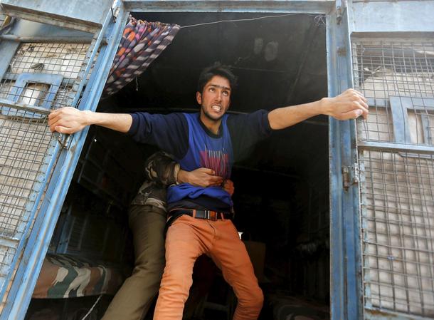 A supporter of Kashmiri lawmaker Rashid attempts to jump from a police vehicle after he was detained
