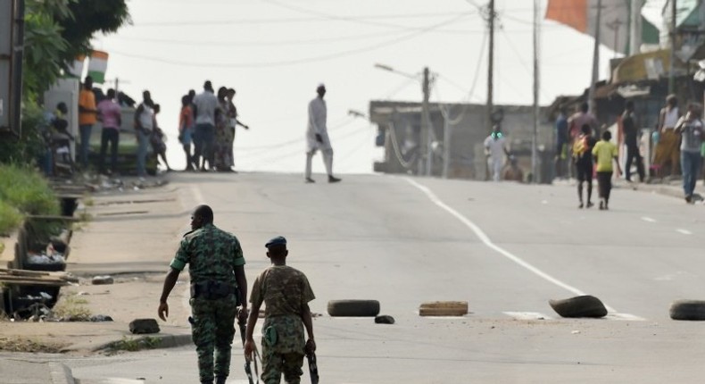 Soldiers patrol near tyres blocking the road in the Plateau business district of the Ivorian capital Abidjan on January 7, 2017 as angry troops took to the streets demanding salary hikes