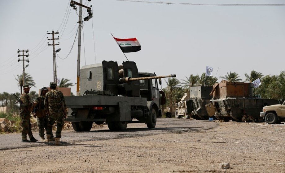 Shi'ite fighters stand with their weapons on the outskirts of Saqlawiya