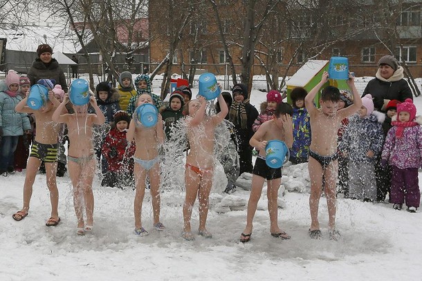 Children watch their classmates pour cold water on themselves, under the watch of fitness coach Oksa