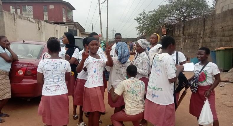 Students from Ojota Senior Secondary School, Ojota, Lagos, signing autographs on their uniforms after last SSCE paper.