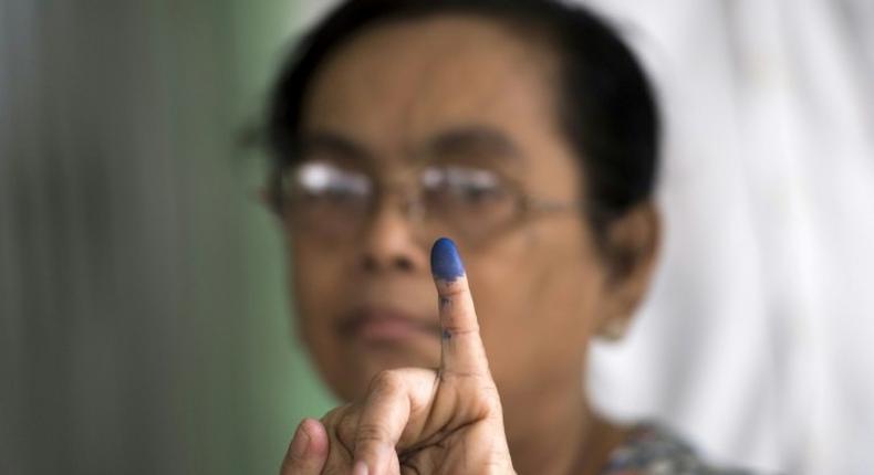 A woman shows her finger, which was inked after she cast her vote in a by-election, in a polling station in Yangon, Myanmar