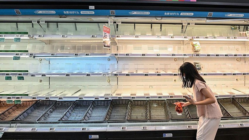 Žena stoji sa kesom crnog luka ispred prazne police u supermarketu u Hongkongu | Foto: Getty Images