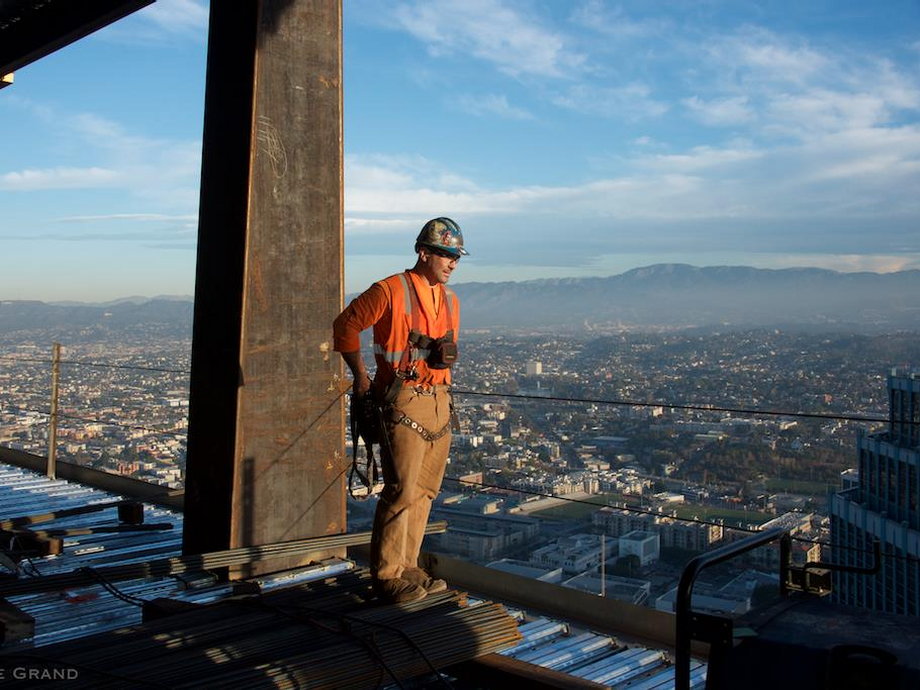 A construction worker stands on one of the upper levels. The tower overlooks the whole of the city and surrounding mountains.