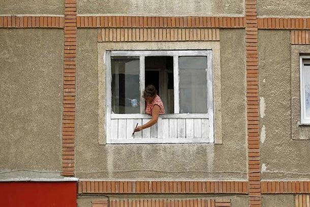 Mieszkanka Aninoasy maluje ramy okienne. Rumunia bieda
