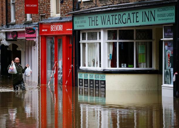 A man carries groceries into a flooded pub in York city centre