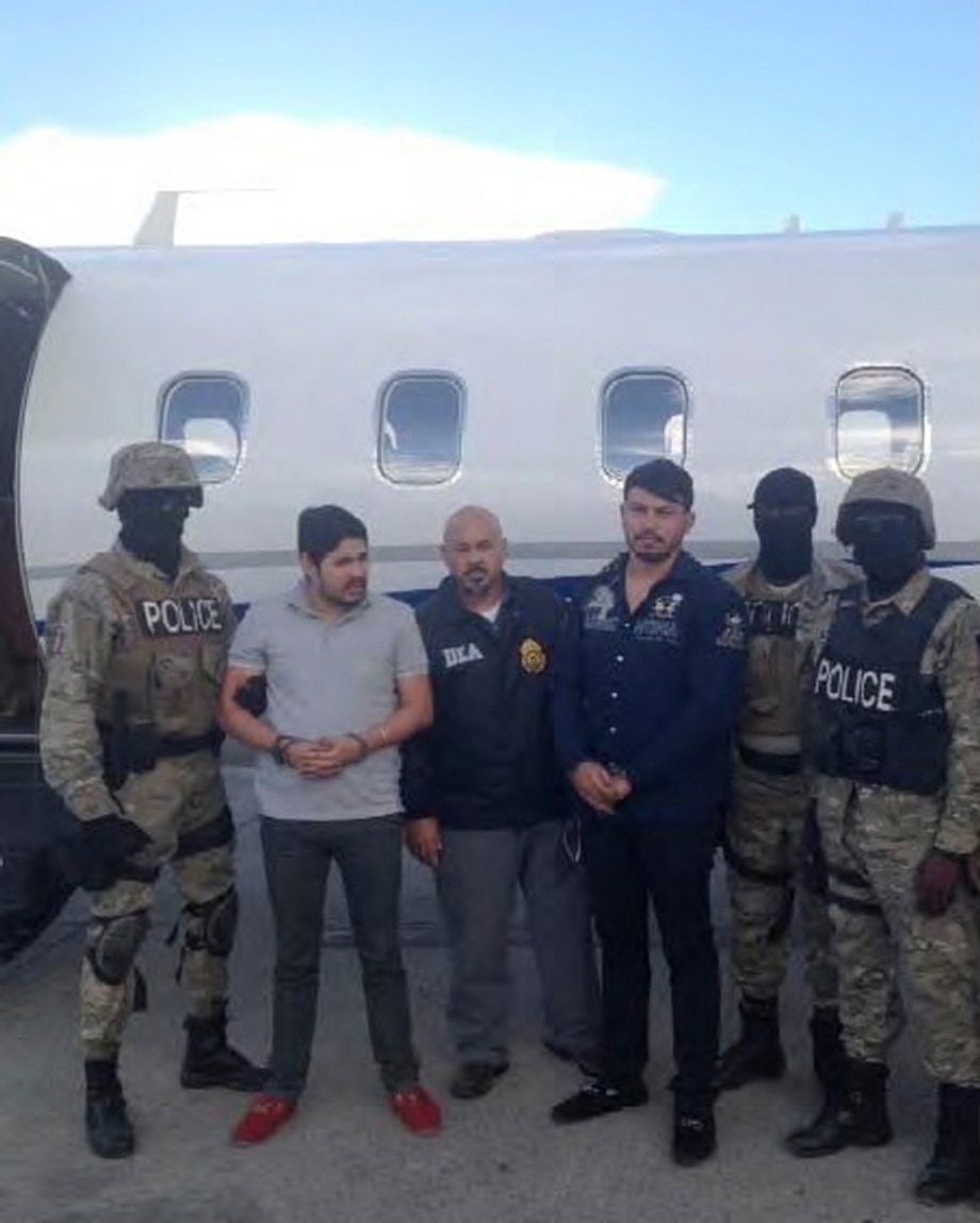 Efrain Antonio Campo Flores, second from left, and Franqui Francisco Flores de Freitas stand with law-enforcement officers in this November 12, 2015, photo after their arrest in Port Au Prince, Haiti.