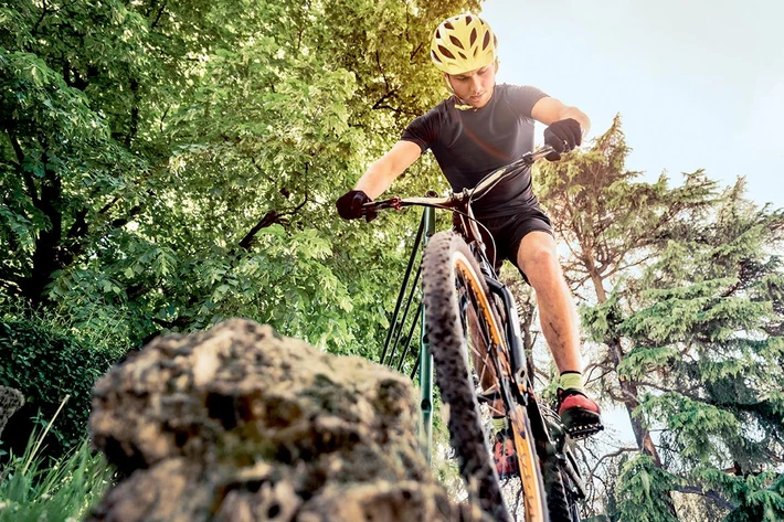 Sport guy making downhill on his mountain bike