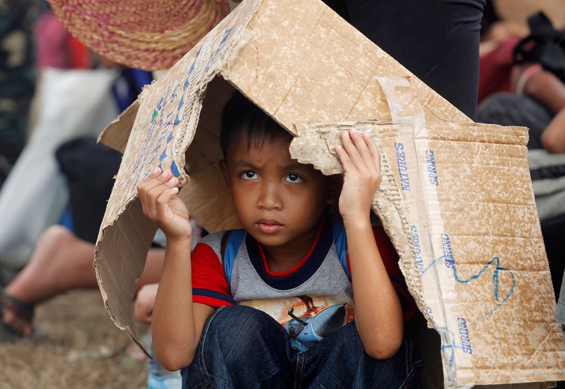 Chłopiec kryje się przed deszczem pod kartonem. Tajfun Haiyan, który przeszedł nad Filipinami, zniszczył dziesiątki tysięcy budynków i pozbawił dachu nad głową setki tysięcy ludzi