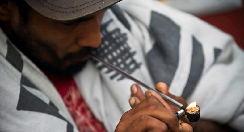 A drug addict lights an improvised pipe on the street in Cracolandia in 2014