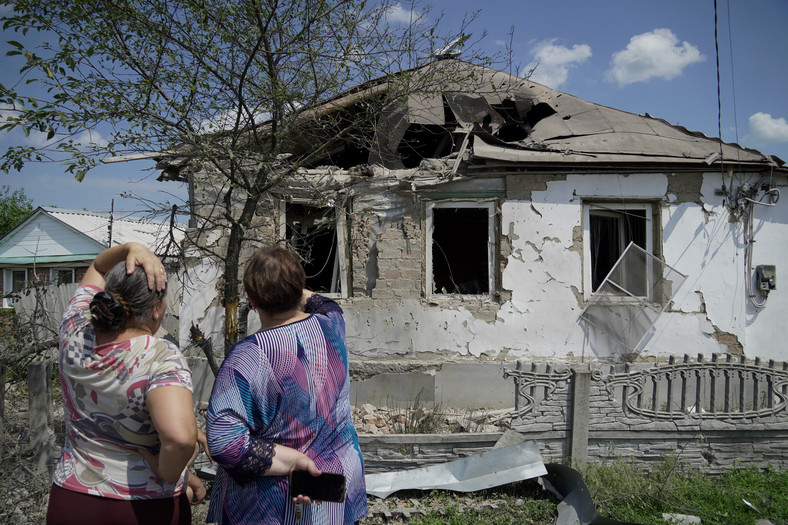 Kobiety patrzą na zniszczony dom w pobliżu granicy z Ukrainą w obwodzie białogrodzkim