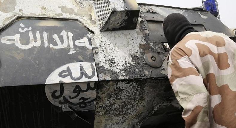 A Chadian soldier peers into a burnt armoured vehicle, which the Chadian military say belonged to insurgent group Boko Haram, after the Chadians destroyed it during battle in Gambaru, February 26, 2015.  REUTERS/Emmanuel Braun