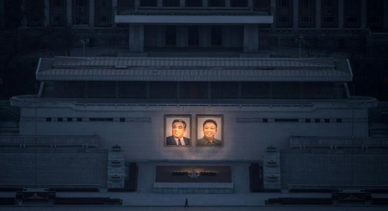 A pedestrian passes portraits of late North Korean leaders Kim Il-Sung (L) and Kim Jong-Il in Pyongyang, seen from the landmark Juche tower on February 17, 2017