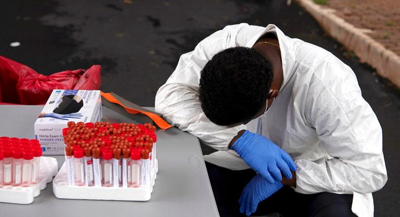 A healthcare worker takes a break as people wait in line in vehicles for coronavirus testing. [AFP]