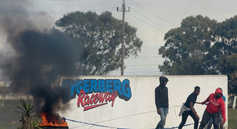 Young men haul a burning tyre during protests at Tygerberg Raceway near Cape Town. The motor-racing venue was invaded on August 6 by people demanding land