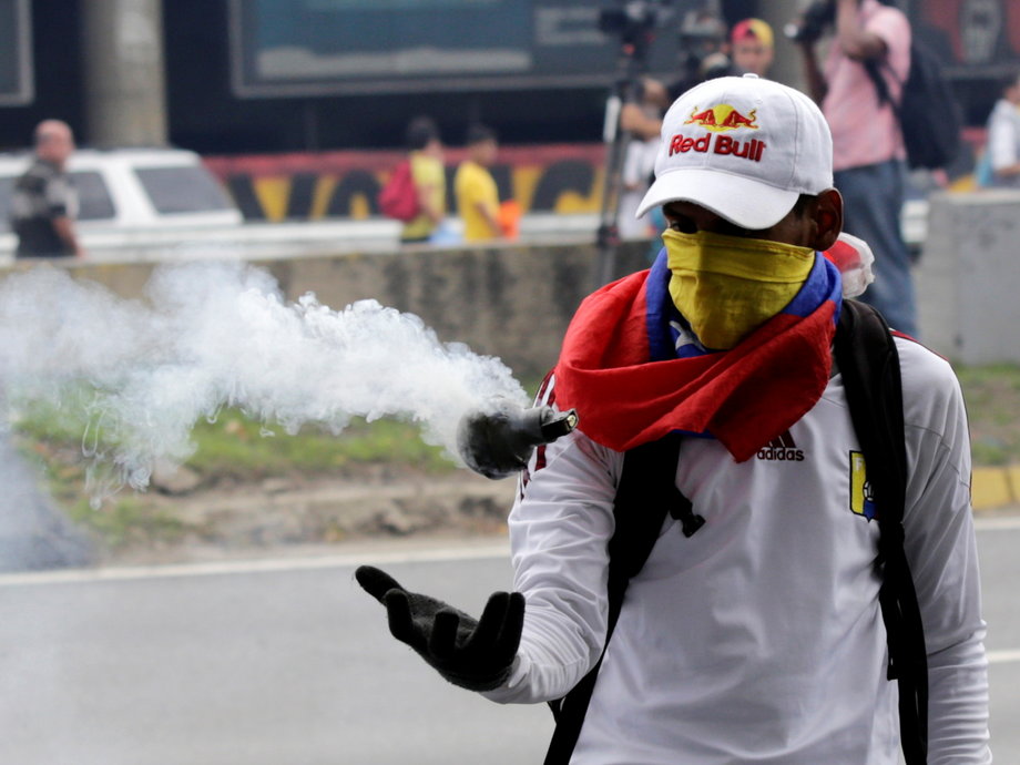 An opposition supporter catches a tear-gas bomb during clashes with riot policemen in a rally to demand a referendum to remove President Nicolas Maduro in Caracas.