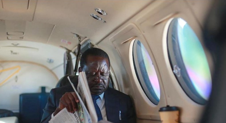 ODM leader Raila Odinga reading a newspaper in a plane