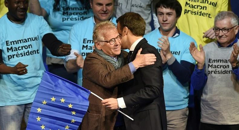 Emmanuel Macron clasps a EU flag as he hugs famous MEP Daniel Cohn-Bendit (L)