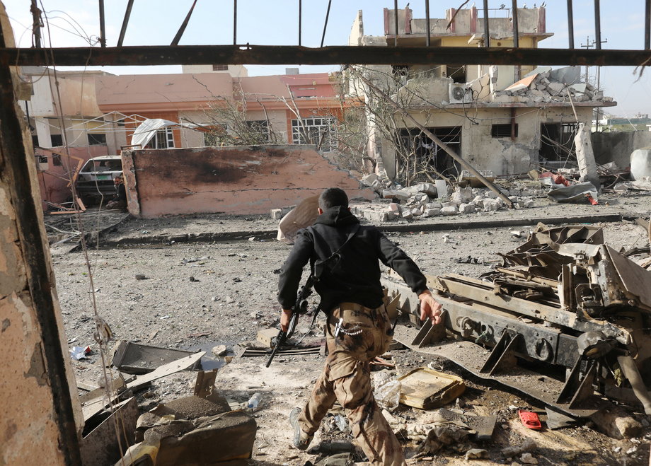 An Iraqi special forces soldier runs across a street after an Islamic State suicide car bomb attack during gunfight in Tahrir neighborhood of Mosul, Iraq, November 17, 2016.