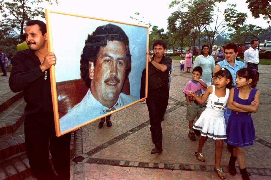 Two men carry a picture of Pablo Escobar through the streets of Medellin December 2, 1994, on the first anniversary of his death. Hundreds of admirers packed a memorial service for the slain cocaine king, proclaiming undying loyalty to the dead drug lord.