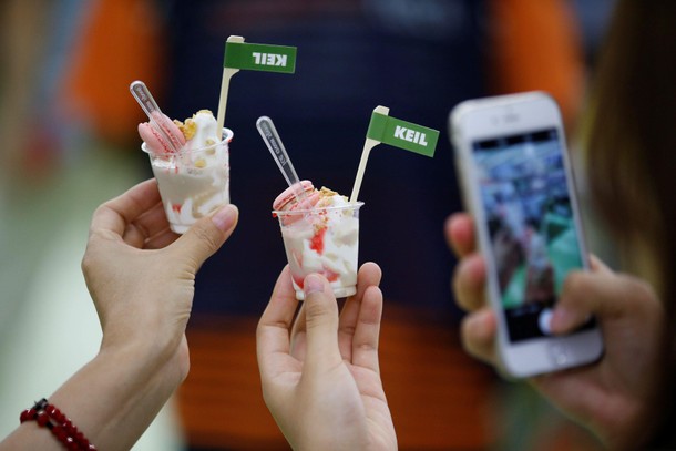 A woman takes photographs of sample foods made up of edible insect powder in Seoul