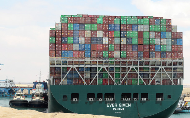 epa09098677 Egyptian tugboats try to pull out the Ever Given container ship stranded in the Suez Canal, Egypt, 26 March 2021. The large container ship Ever Given ran aground in the Suez Canal on 23 March, blocking passage of other ships and causing a traffic jam for cargo vessels. The head of the Suez Canal Authority announced on 25 March that 'the navigation through the Suez Canal is temporarily suspended' until the floatation of the Ever Given is completed. Its floatation is being carried out by eight large tugboats that are towing and pushing the grounding vessel. EPA/KHALED ELFIQI Dostawca: PAP/EPA.