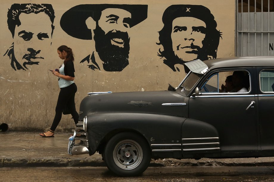 A woman walks past a mural depicting Cuban Communist Party founder Julio Antonio Mella, left, Cuban revolutionary leaders Camilo Cienfuegos, center, and Che Guevara in the Habana Vieja neighborhood, in Havana, Cuba, January 24, 2015.