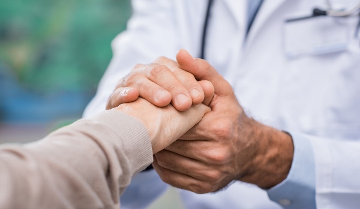 Close up of doctor hand reassuring her female patient at hospital. Closeup hands of medical doctor carefully holding patient's hands. Kind doctor giving real support for patient.