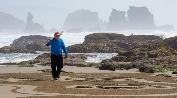 Labirintusokat készít az idős férfi a homokba